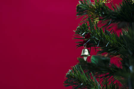 close up small bell on christmas tree on red の写真素材
