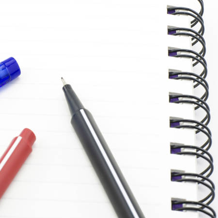 black red and blue pen with notebook isolated on white backgroundの写真素材