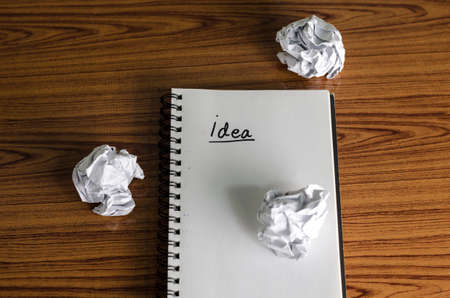 notebook write idea word with crumpled on wooden backgroundの写真素材