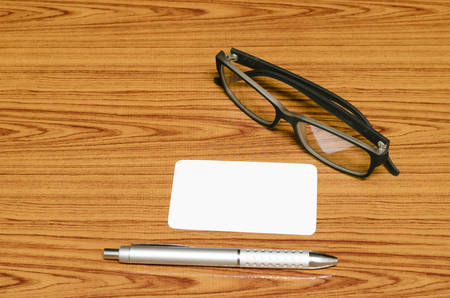 business card and pen with glasses on wood backgroundの写真素材