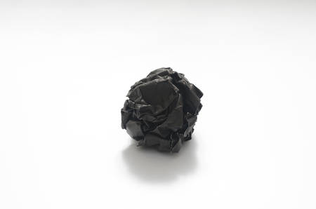 black crumpled paper ball on a white backgroundの写真素材