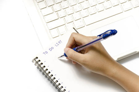 woman hand writing with pen on notebook write to do word and laptop over white background