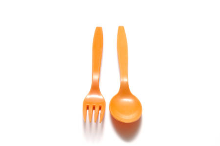 orange plastic spoon and fork on a white background