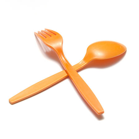orange plastic spoon and fork on a white の写真素材