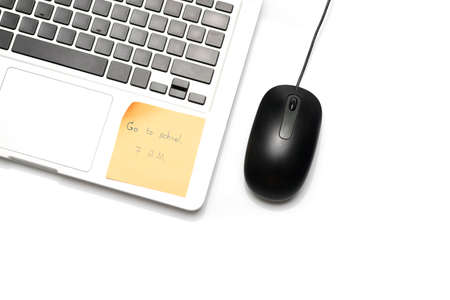 laptop and mouse with sticky note isolated on white background write go to school 7 A.M.