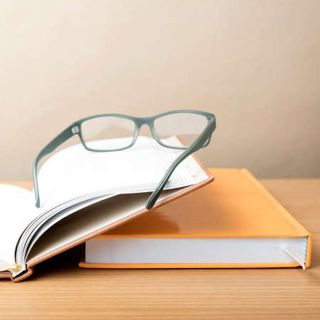 group of book and eyeglasses on wood background