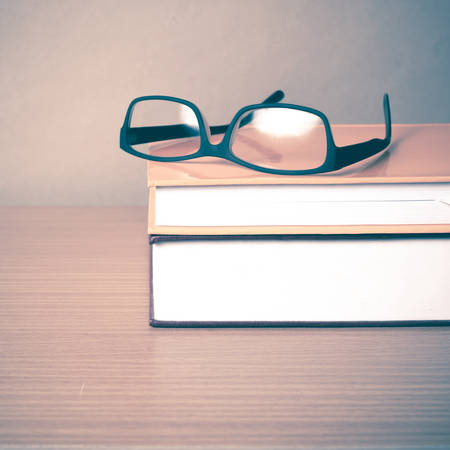 book and eyeglasses on wood background vintage styleの写真素材