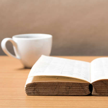 open book with coffee on wood background