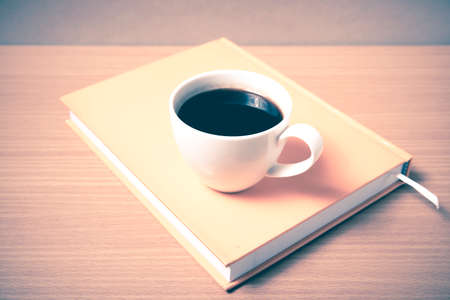 coffee cup on orange book on wood background vintage styleの写真素材
