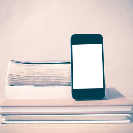 stack of book and smart phone on wood background vintage styleの写真素材