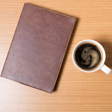 brown book with black coffee on wood backgroundの写真素材