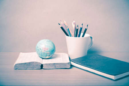 book and earth ball with color pencil on wood background vintage styleの写真素材