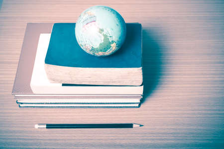 book and earth ball with black pencil on wood background vintage style