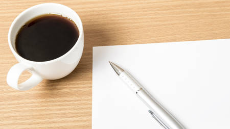 coffee cup with white paper and pen on wood backgroundの写真素材