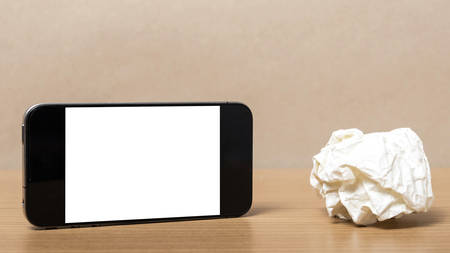 smart phone and crumpled paper on wood backgroundの写真素材