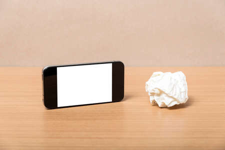 smart phone and crumpled paper on wood backgroundの写真素材