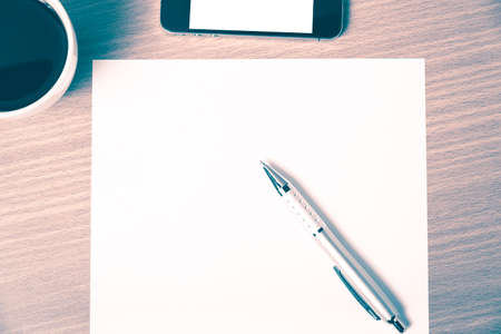 paper and pen with coffee cup and smart phone on wood background vintage styleの写真素材