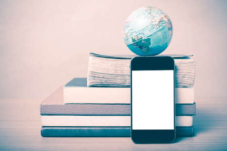 book and earth ball with smart phone on wood background vintage styleの写真素材