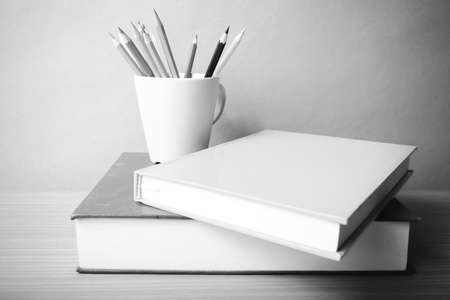 stack of book with color pencil on wood table background black and white color tone style