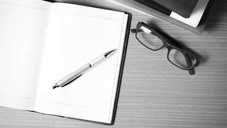 open notebook with stack of book on wood background black and white color tone style
