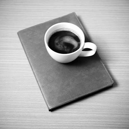 brown book with black coffee on wood background black and white color tone styleの写真素材