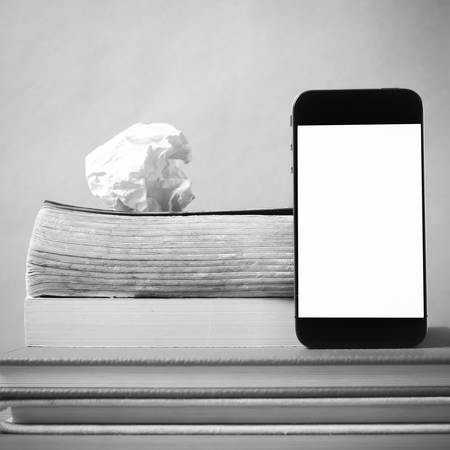 stack of book and smart phone on wood background black and white color tone styleの写真素材