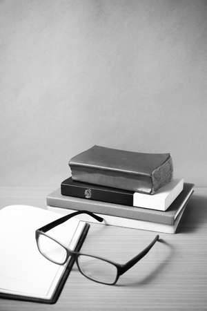 open notebook with stack of book on wood background black and white color tone styleの写真素材