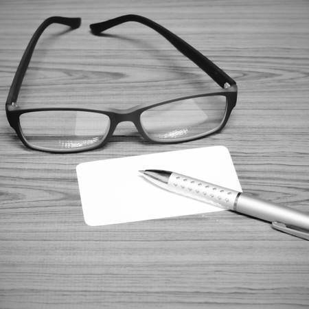 business card and pen with glasses on wood background black and white color tone styleの写真素材