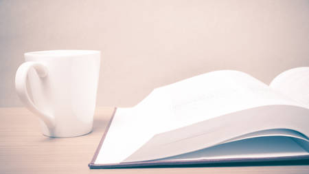 book and coffee mug on wood background vintage styleの写真素材
