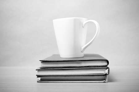 stack of book with coffee mug on wood background black and white tone styleの写真素材