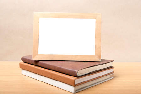 stack of book and photo frame on wood background