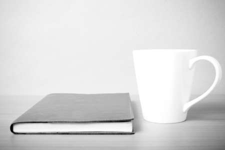 book and coffee mug on wood background black and white tone styleの写真素材
