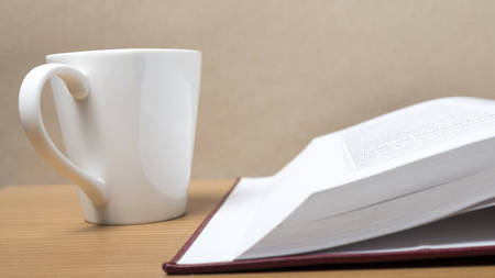 book and coffee mug on wood background