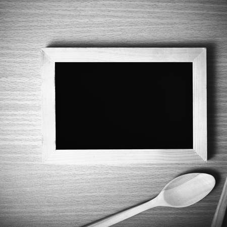 blackboard and wooden spoon on table black and white color tone styleの写真素材