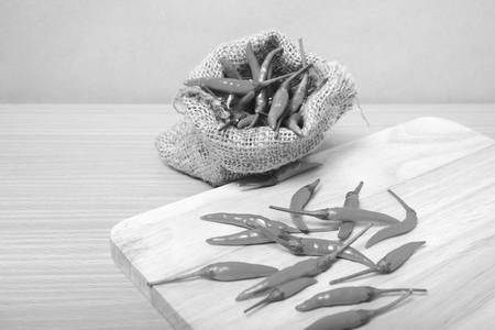 red chili peppers on cutting board over wood table background black and white tone color styleの写真素材