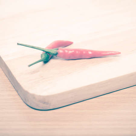 red chili peppers on cutting board over wood table background vintage styleの写真素材