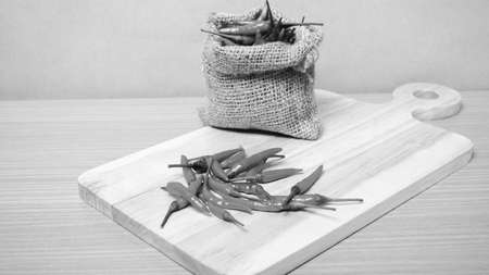 red chili peppers on cutting board over wood table background black and white tone color styleの写真素材