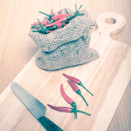 red chili peppers on cutting board over wood table background vintage styleの写真素材