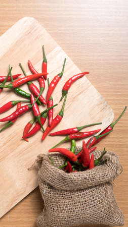 red chili peppers on cutting board over wood table backgroundの写真素材