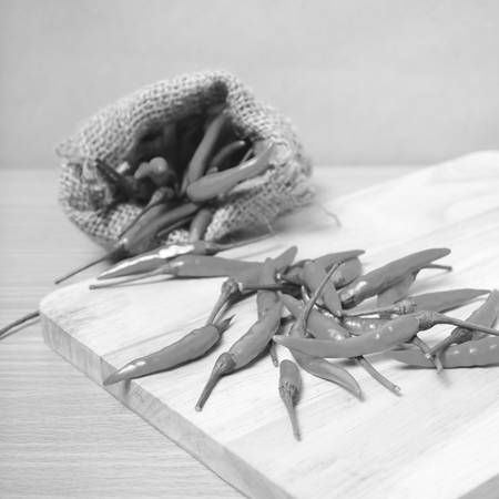 red chili peppers on cutting board over wood table background black and white tone color styleの写真素材