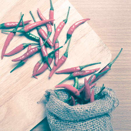 red chili peppers on cutting board over wood table background vintage styleの写真素材