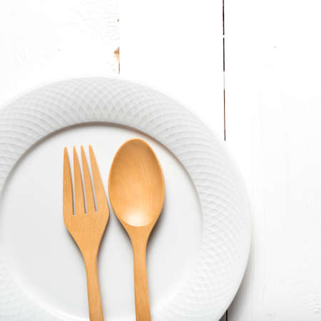 wood spoon and fork with dish over white table backgroundの写真素材
