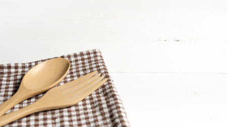 wood spoon and fork on kitchen towel over white backgroundの写真素材