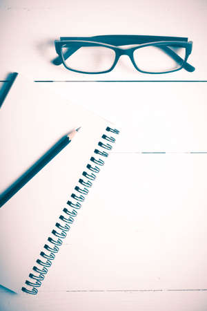 pencil and notepad with eyeglasses over white table view from above vintage styleの写真素材