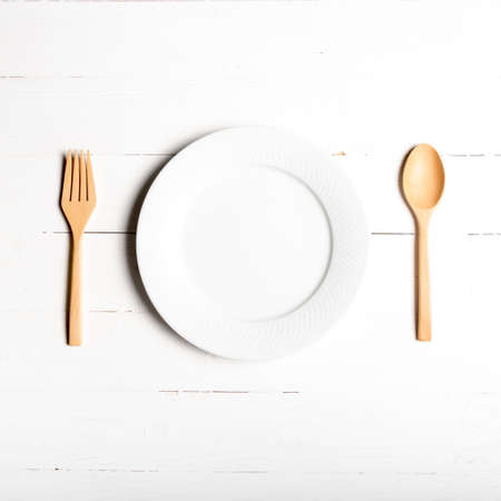 wood spoon and fork with dish over white table backgroundの写真素材
