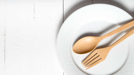 wood spoon and fork with dish over white table backgroundの写真素材