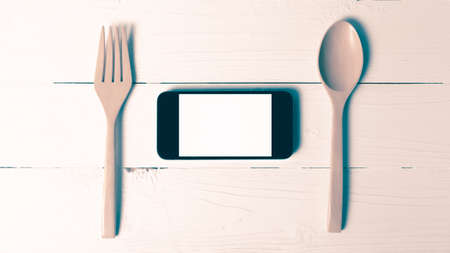 spoon and smart phone concept eating social over table background vintage styleの写真素材