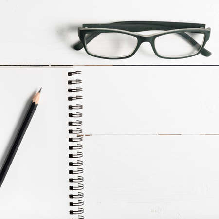 pencil and notepad with eyeglasses over white table view from aboveの写真素材