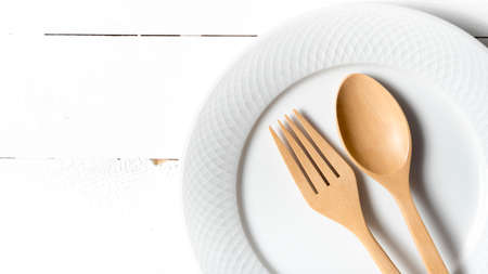 wood spoon and fork with dish over white table backgroundの写真素材
