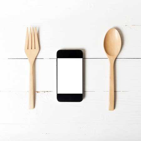 spoon and smart phone concept eating social over white table backgroundの写真素材